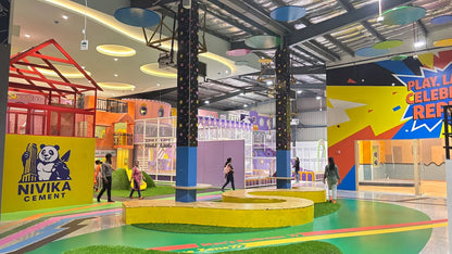 A colorful indoor playground with children playing and adults supervising.
