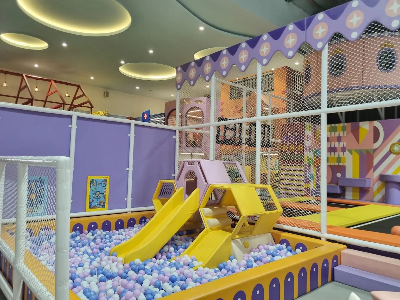 A colorful indoor playground with a ball pit, slides, and climbing structures for children.