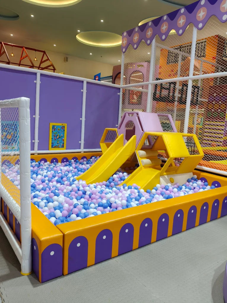 A colorful indoor playground with a ball pit and slides for young children.