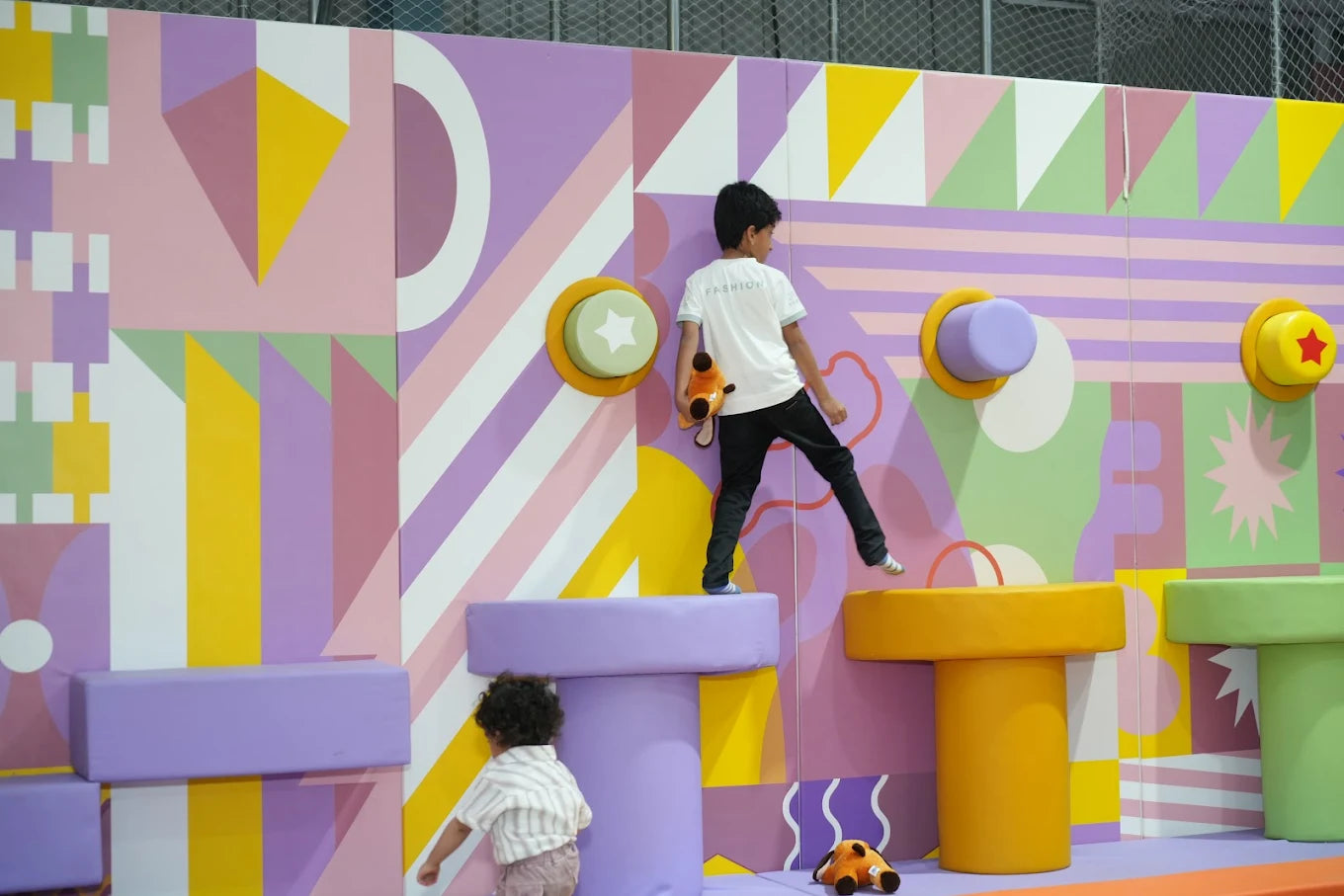 Two children play on a colorful, geometric climbing structure.