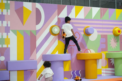Two children play on a colorful, geometric climbing structure.
