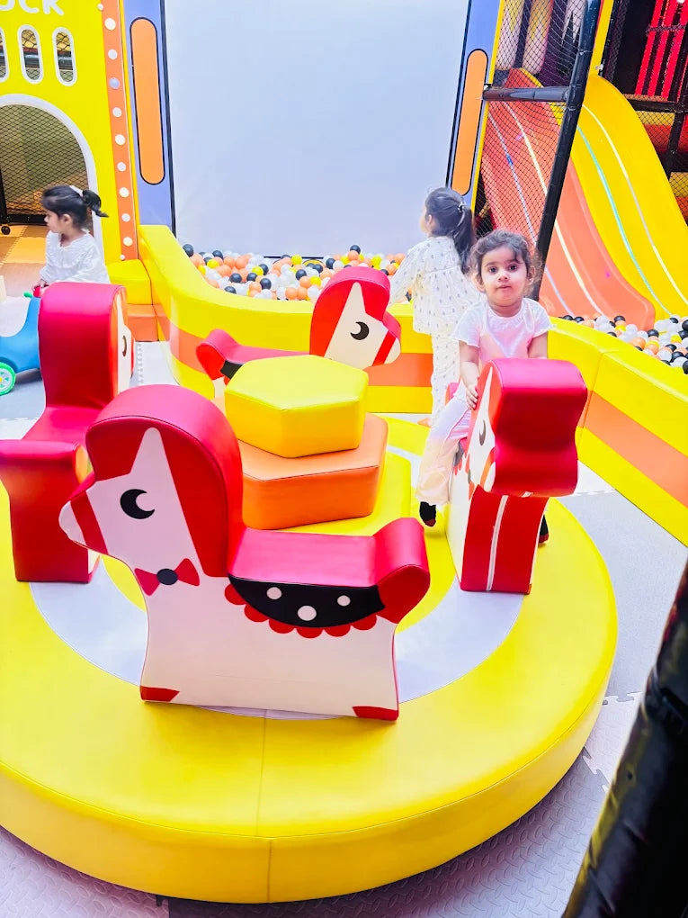 Toddlers playing on animal-shaped soft seating around a colorful round platform near a ball pit at Sector 12 Faridabad play area