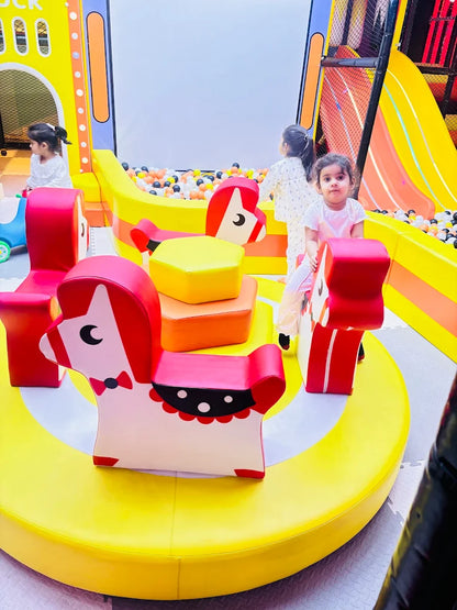 Toddlers playing on animal-shaped soft seating around a colorful round platform near a ball pit at Sector 12 Faridabad play area