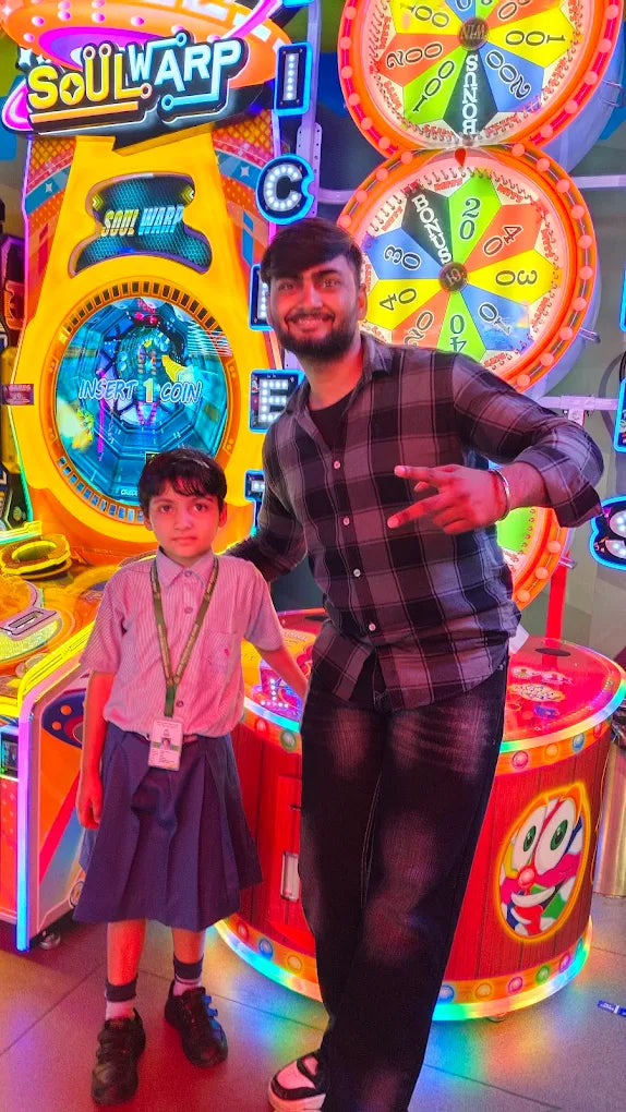 Man and child posing by bright Soul Warp arcade game with colorful spinning prize wheels at Sky Gamer Sector 12 Faridabad