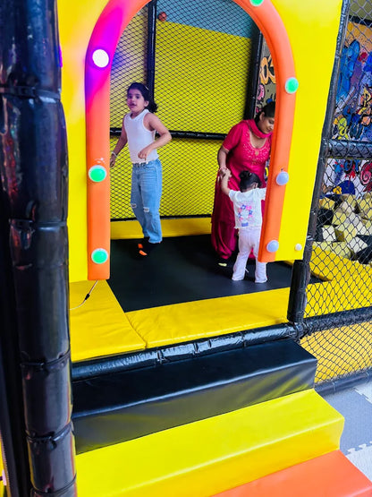 Children playing on a colorful inflatable bounce house with a woman supervising.