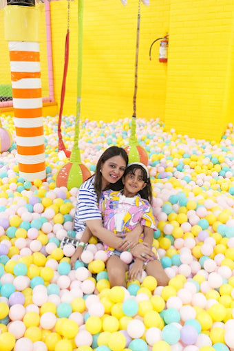 Mother and daughter enjoying colorful ball pit with hanging swings in a bright indoor play area at SkyJumper Kids Trampoline Park