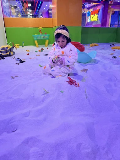 Child playing in a snowy play area with toys and colorful walls.