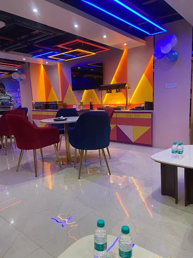 Modern indoor party room with neon lighting, colorful geometric walls, and cozy seating at a kids trampoline park