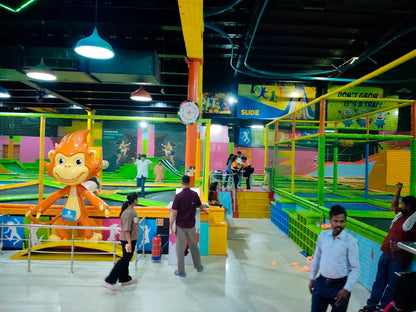 A vibrant indoor trampoline park with children and adults enjoying the attractions, including a large monkey statue.