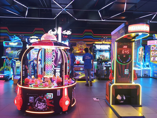 An arcade with various games, including a UFO-themed claw machine and a boxing game, with young adults playing.