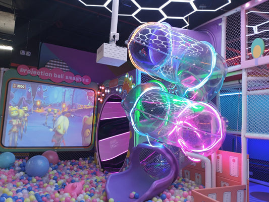 Children's indoor playground with a ball pit, projection game, and colorful tube slides.