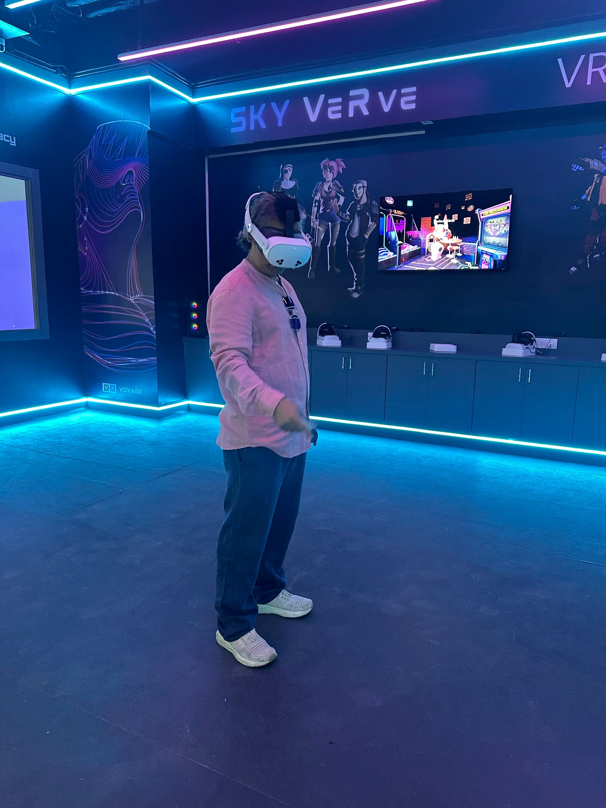 A person wearing a VR headset stands in a neon-lit room with futuristic graphics on the wall.