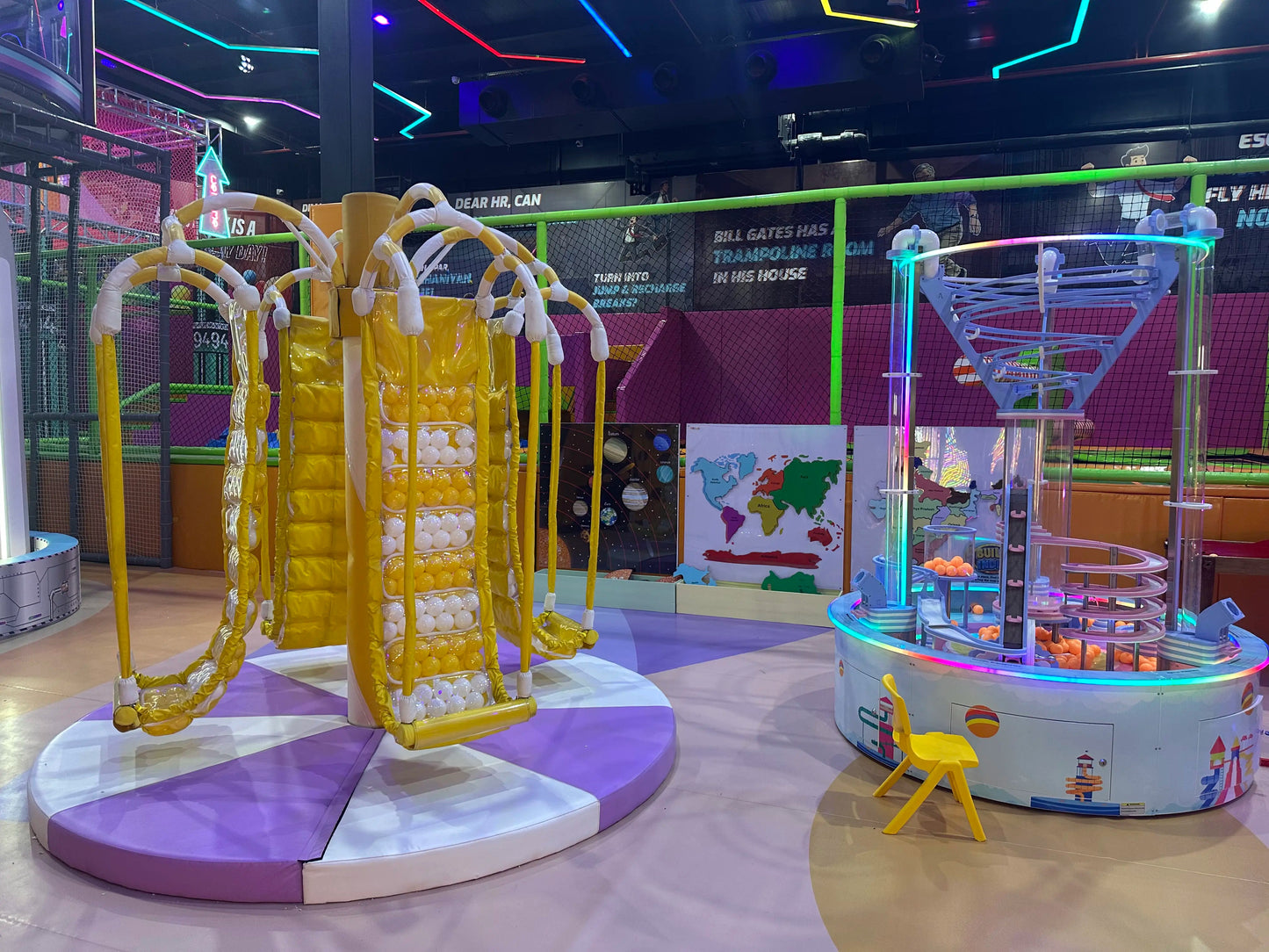 A colorful indoor playground with a spinning ride and a ball pit game.