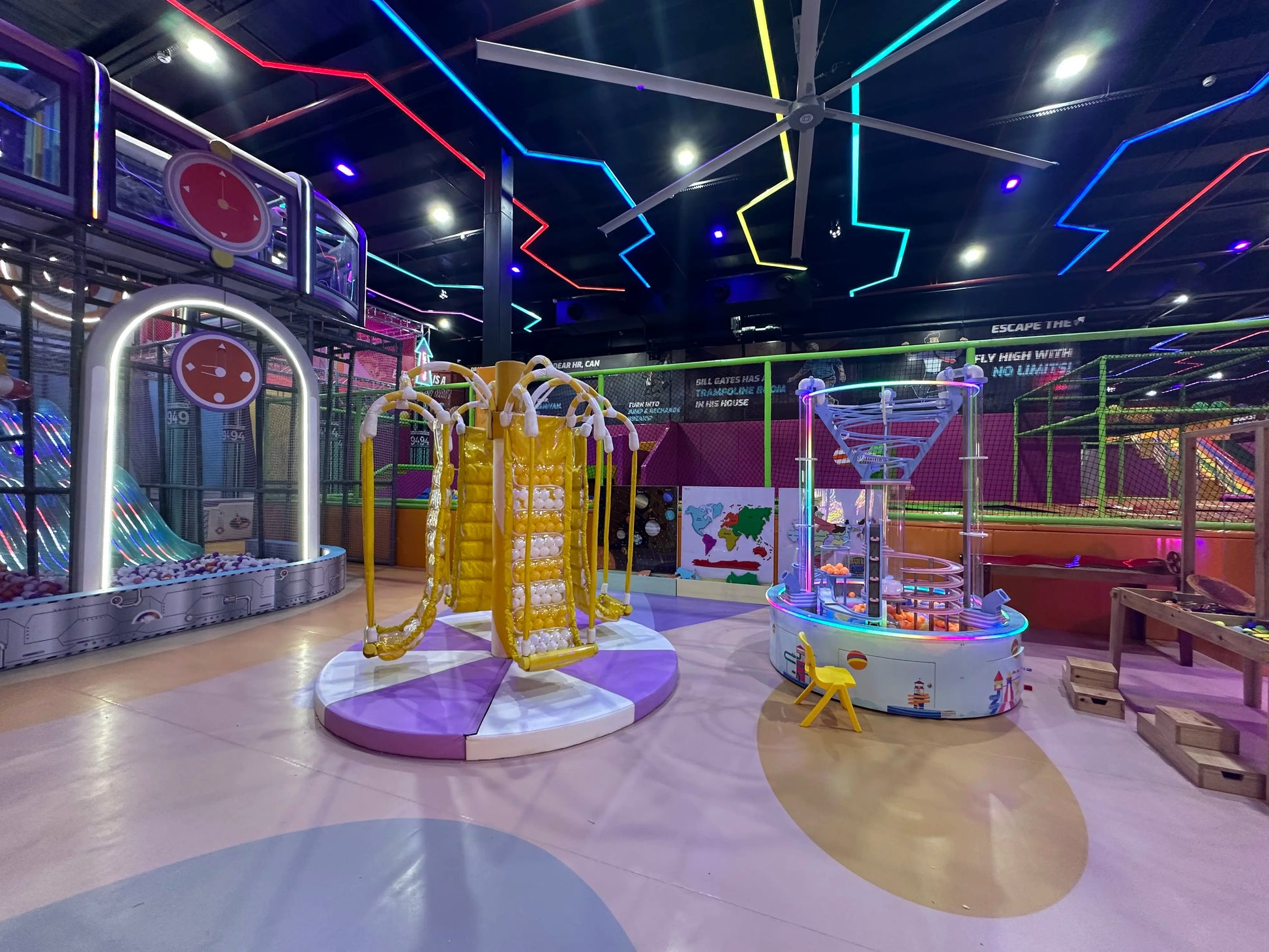 Colorful indoor playground with various equipment and neon lights on the ceiling.