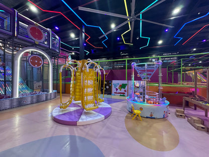 Colorful indoor playground with various equipment and neon lights on the ceiling.