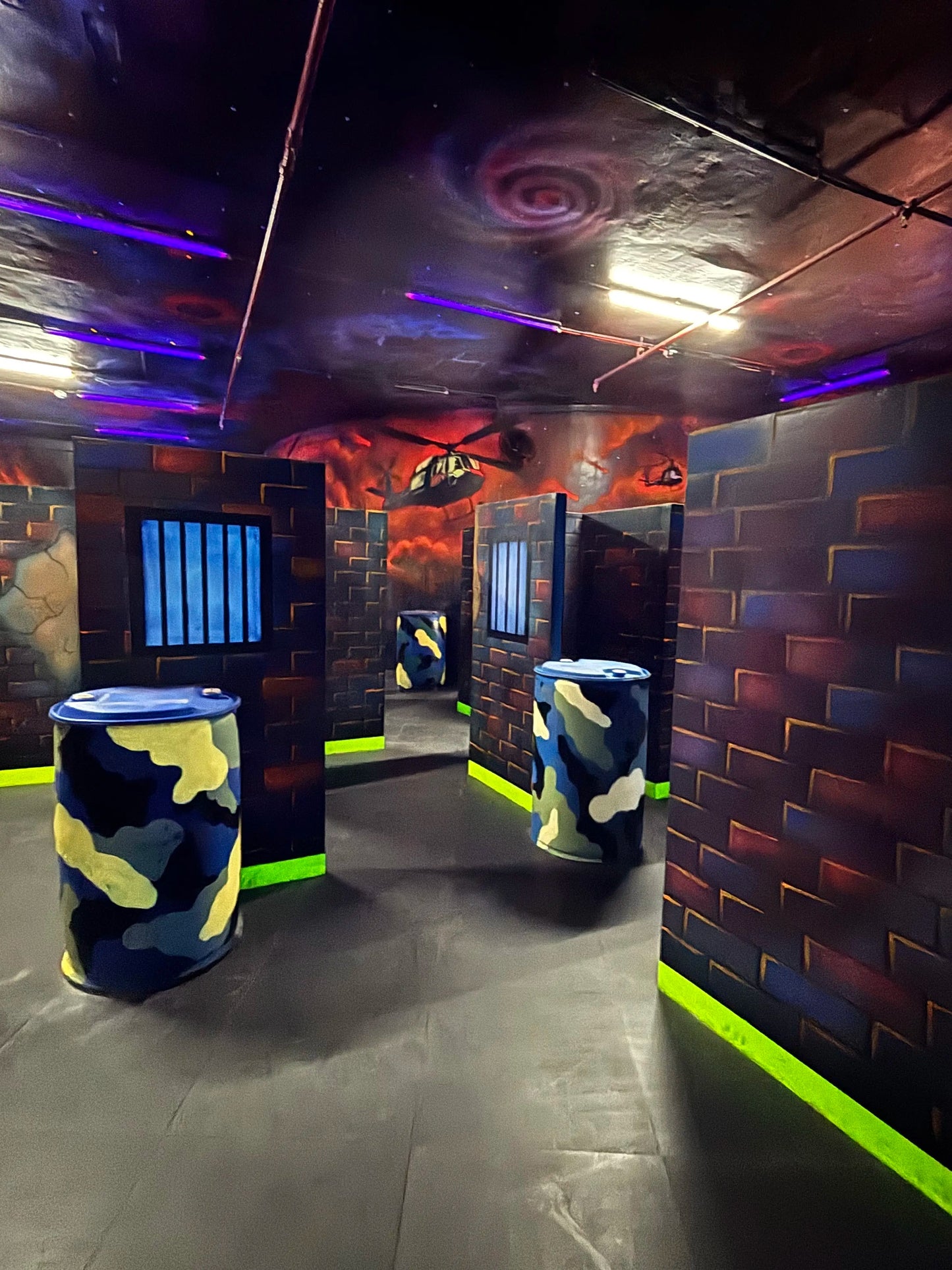 Colorful indoor laser tag arena with walls and ceiling painted in abstract designs.