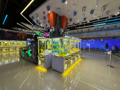 Arcade with claw machines filled with plush toys, decorated with balloons and neon lights.