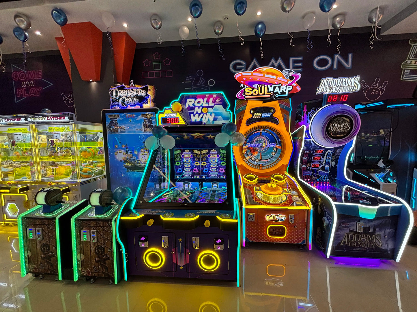 Arcade games with neon lights and balloons, including "Soul Warp" and "The Addams Family."