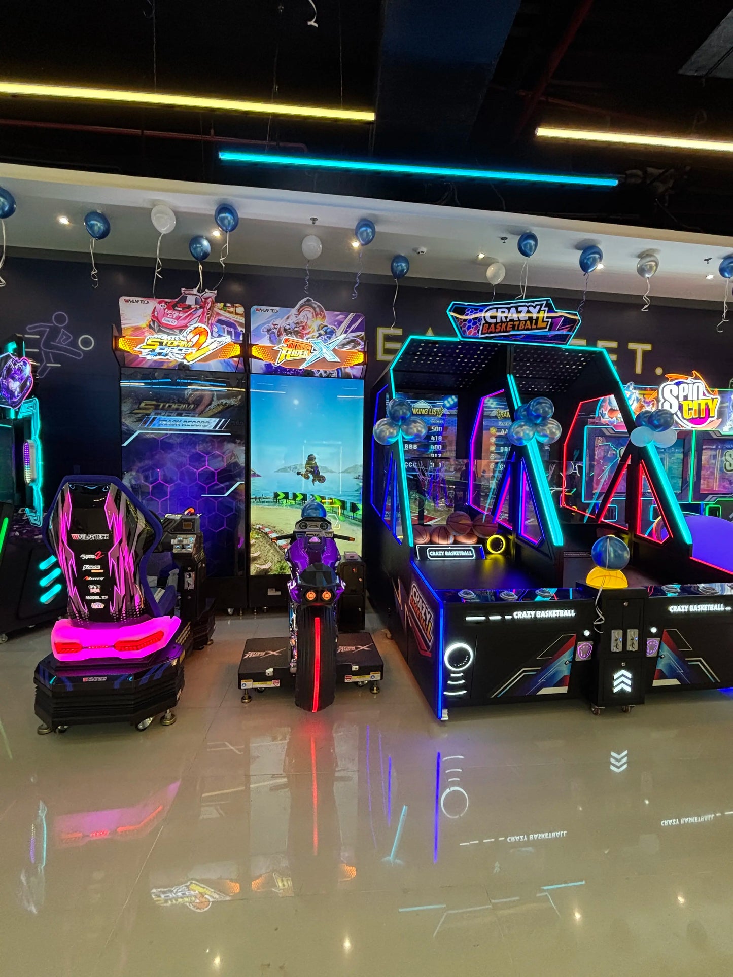 Arcade with racing and basketball games, decorated with balloons.