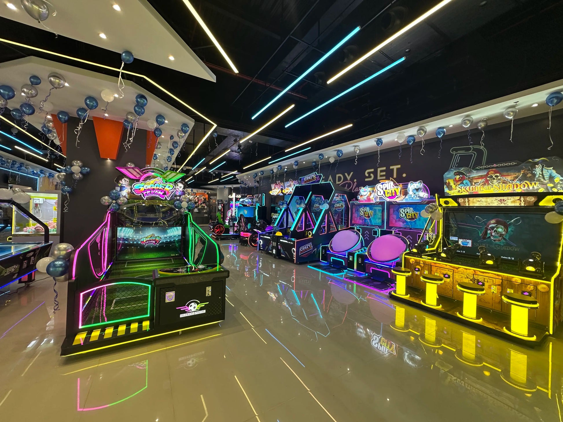 An arcade filled with colorful, neon-lit games and balloons, ready for play.
