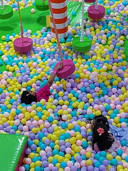 Children play in a ball pit with colorful balls and swings.