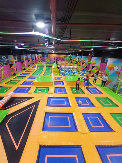 An indoor trampoline park with children and adults jumping and playing.