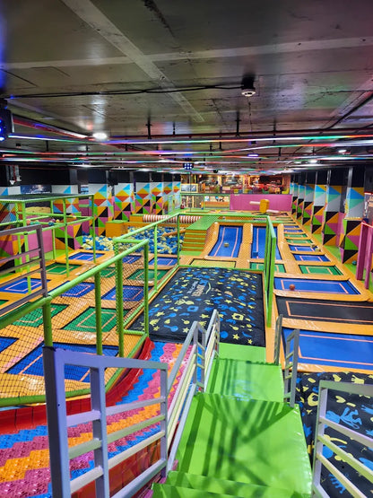 An indoor trampoline park with colorful walls and trampolines, filled with children.