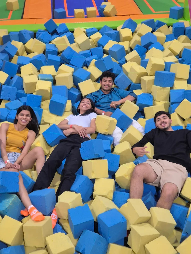 Four young adults are having fun in a foam pit at a trampoline park.