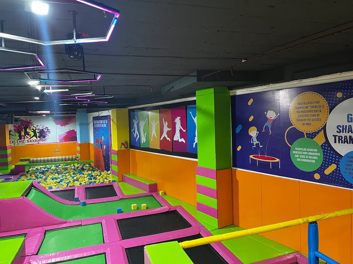 An indoor trampoline park with colorful trampolines, foam pit, and wall art.