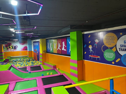 An indoor trampoline park with colorful trampolines, foam pit, and wall art.