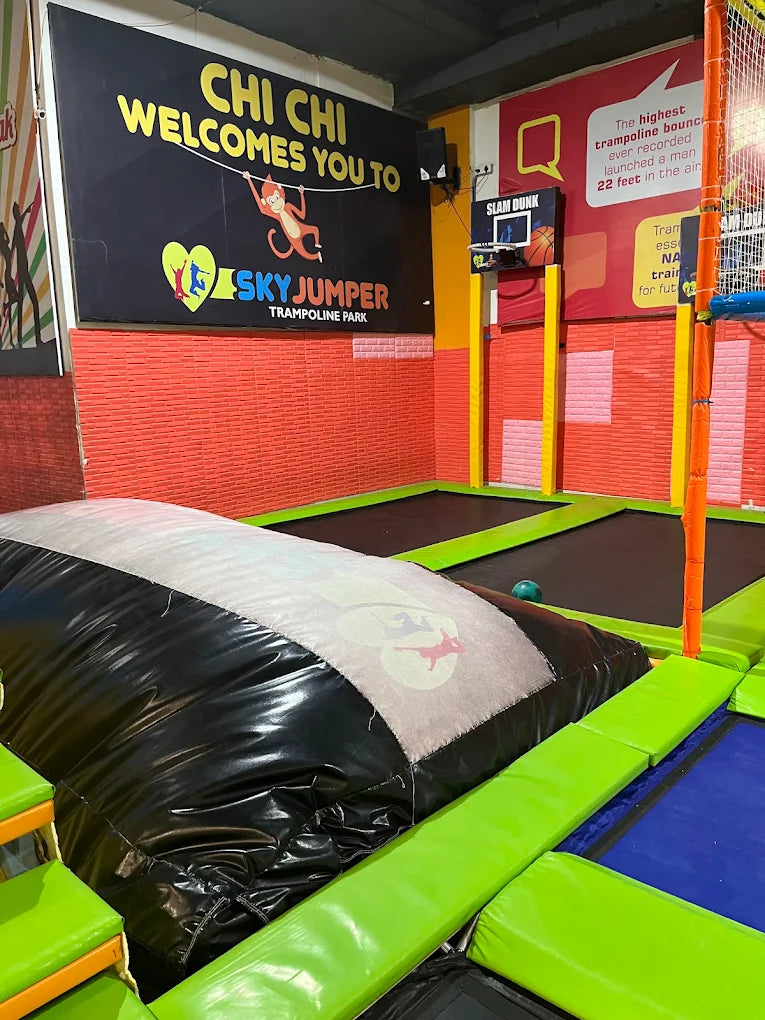 A trampoline park with a large inflatable obstacle and a basketball hoop.