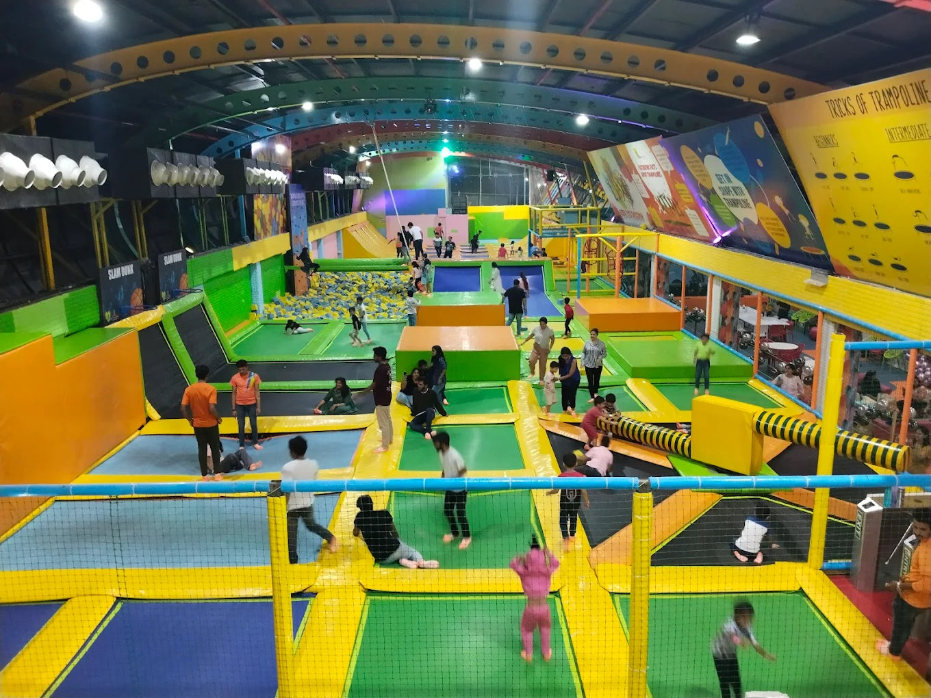 A large indoor trampoline park with many people of various ages jumping and playing.
