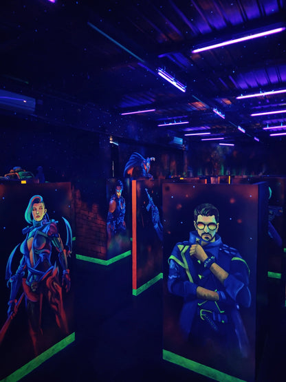 A dimly lit laser tag arena with neon lights and murals of futuristic characters.