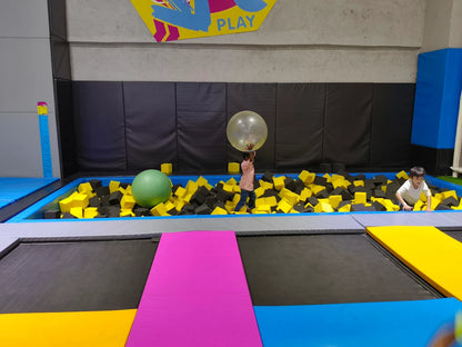 Children play in a foam pit at a trampoline park.