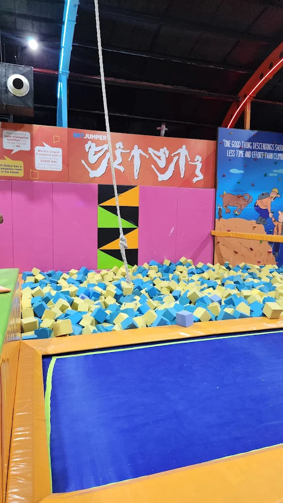 A foam pit filled with blue and yellow cubes at a trampoline park.