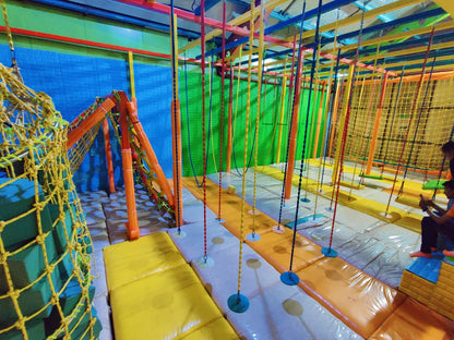 An indoor adventure park with colorful ropes, swings, and nets, where young people are playing.