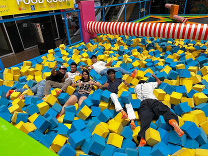 People playing in a foam pit at an indoor playground with colorful equipment.