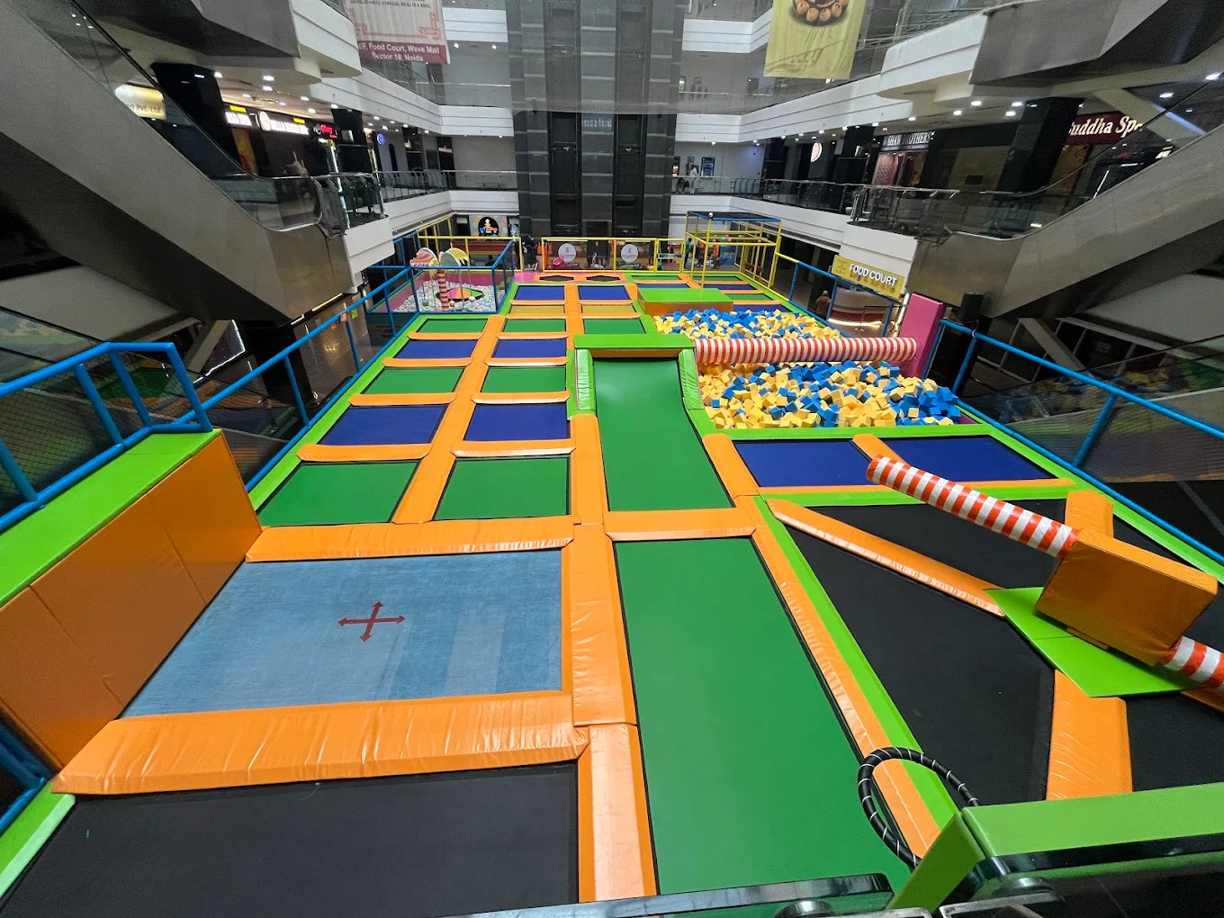 Colorful trampoline park in a mall with various play structures.