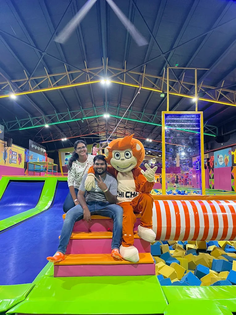 A man and a woman pose with a mascot in a trampoline park.