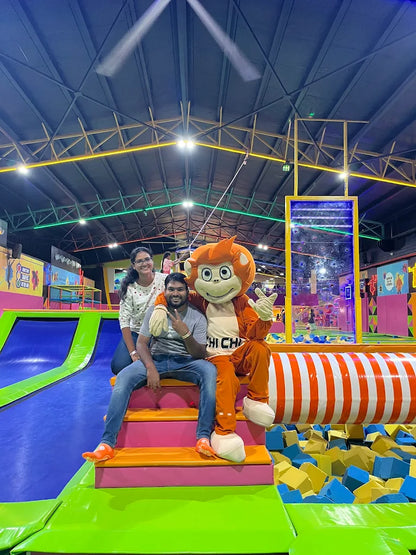 A man and a woman pose with a mascot in a trampoline park.