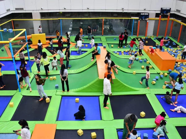 Children playing in a large indoor playground with colorful equipment.