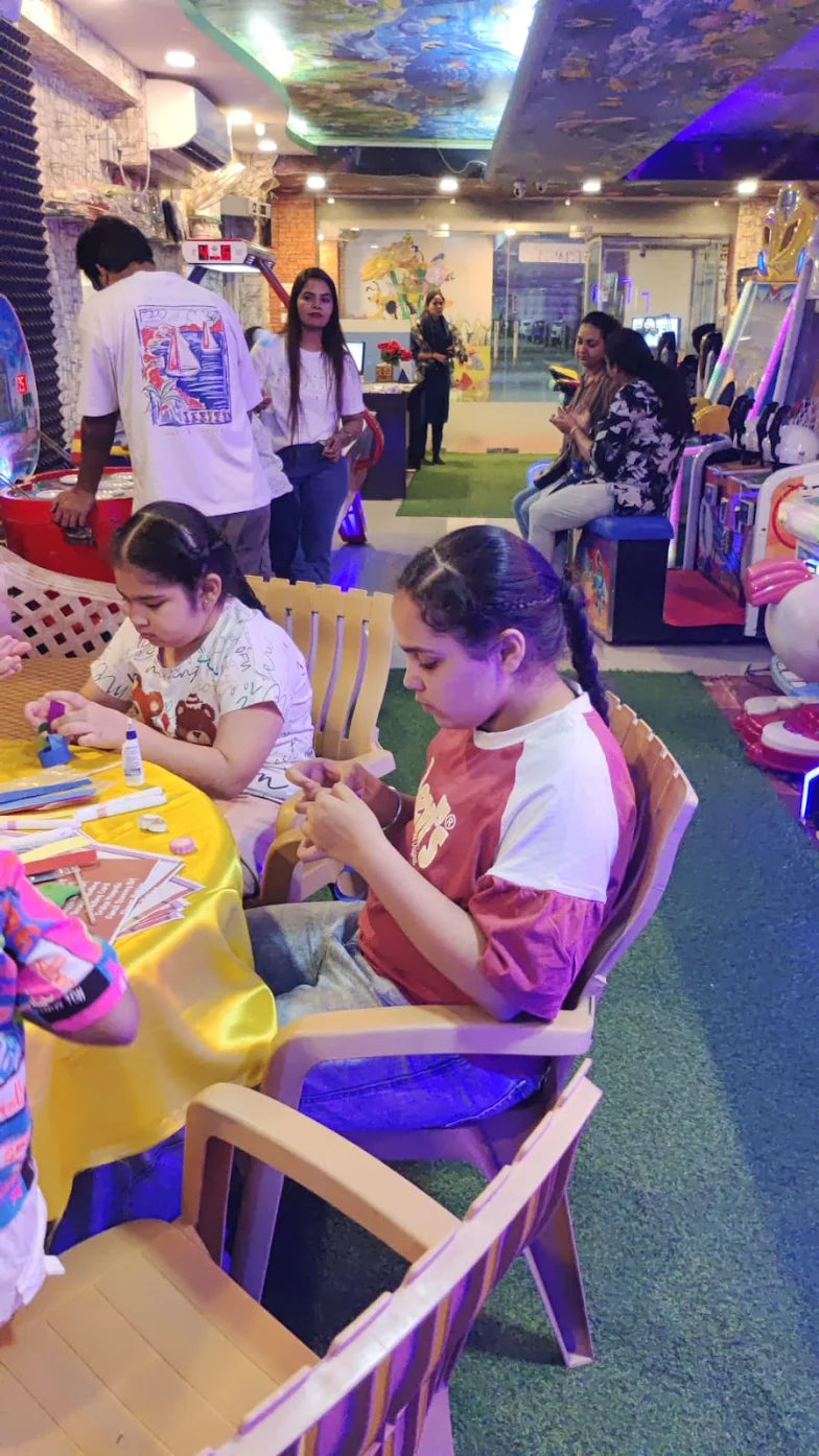 Two young girls are doing crafts at a table in an arcade.