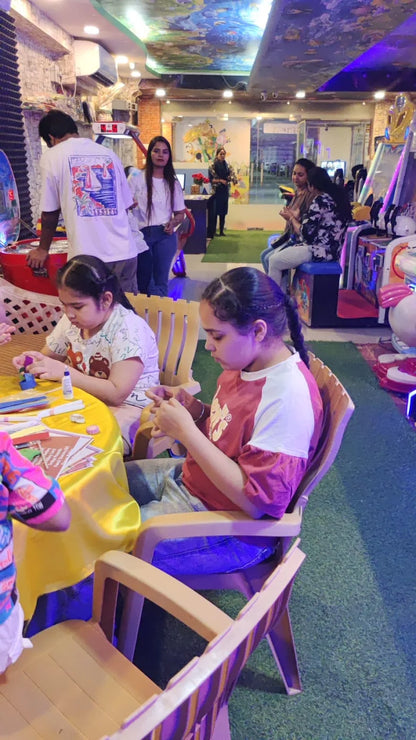 Two young girls are doing crafts at a table in an arcade.