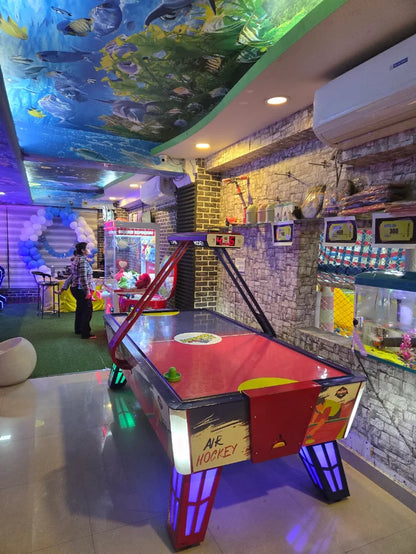 An air hockey table in an arcade with a ceiling mural of underwater life.