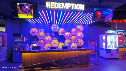 An arcade redemption counter with prizes displayed in hexagonal shelves, lit by neon lights.