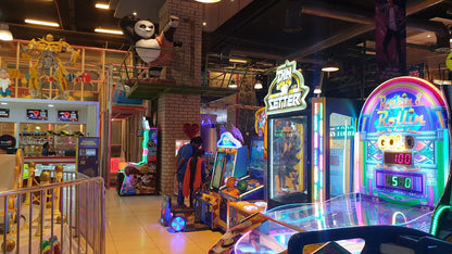 An arcade with various game machines and people playing. A large panda statue is visible.