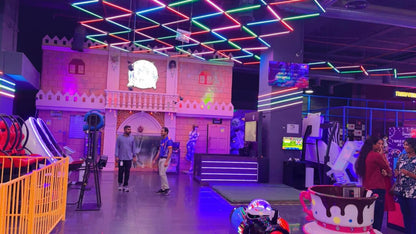 An indoor amusement park with neon lights, arcade games, and young adults.