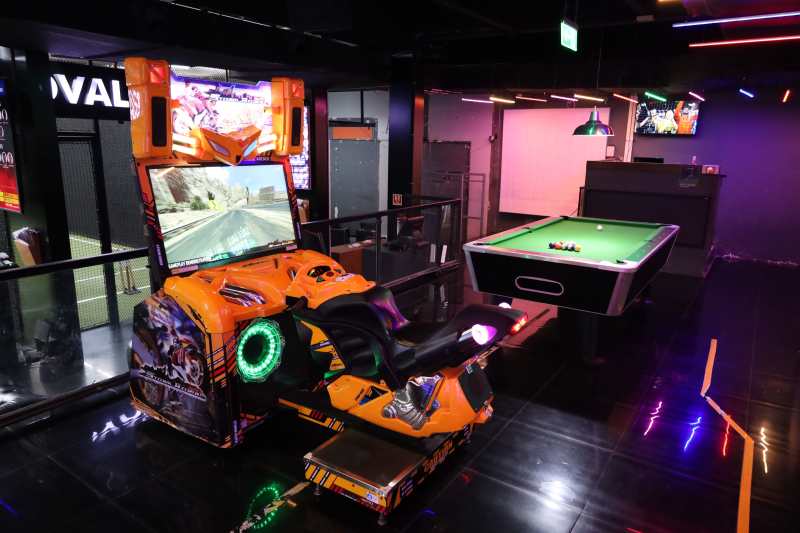 An arcade with a motorcycle racing game and a pool table.