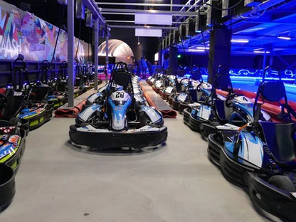 Go-karts lined up on a track with blue lighting.