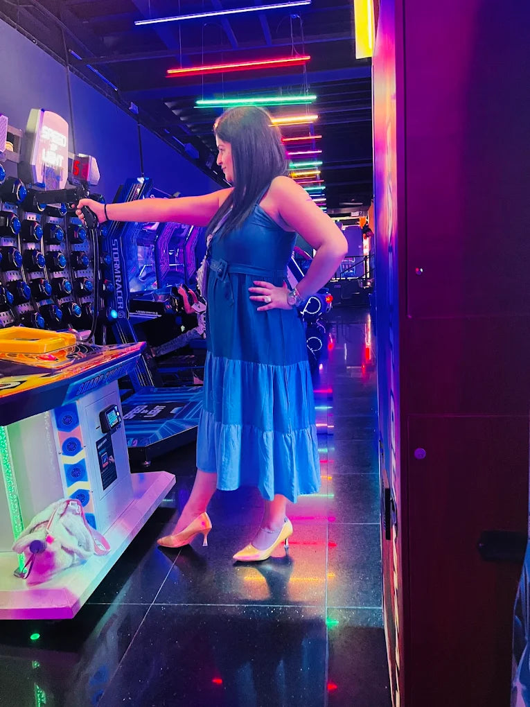 A woman plays an arcade game in a brightly lit arcade.